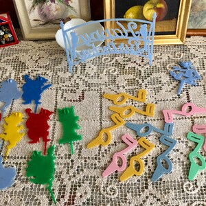 May include: A collection of colorful plastic cake toppers featuring various shapes, including musical notes, animals, and flowers. The toppers are perfect for adding a whimsical touch to any cake.