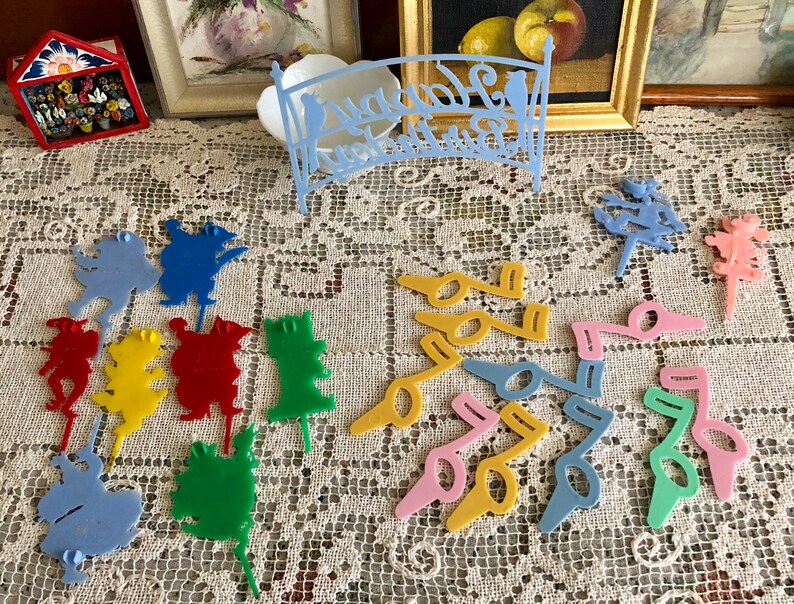 May include: A collection of colorful plastic cake toppers featuring various shapes, including musical notes, animals, and flowers. The toppers are perfect for adding a whimsical touch to any cake.