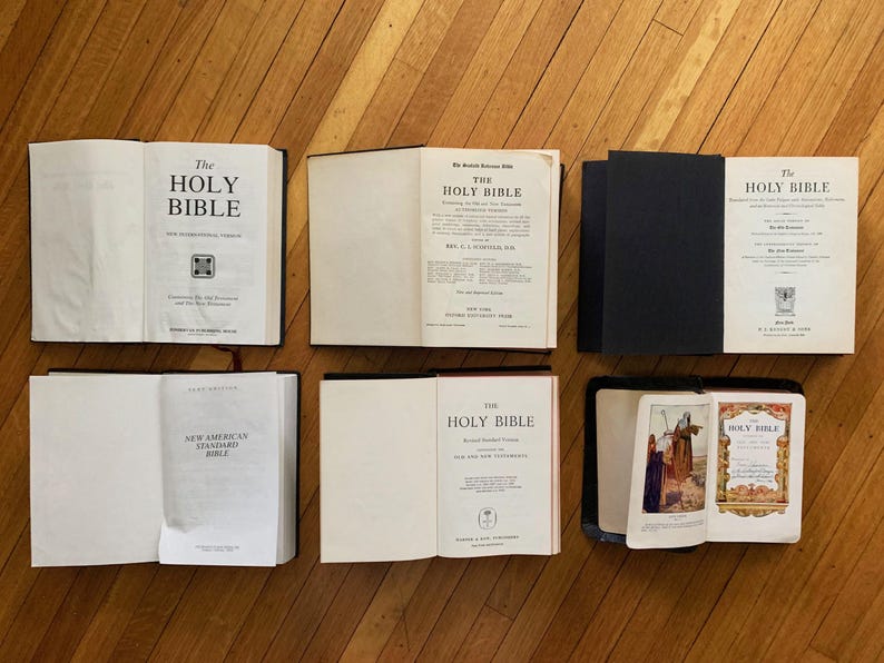 May include: A collection of seven different Holy Bibles, each with a unique cover design. The Bibles are arranged in two rows, with three Bibles in the top row and four Bibles in the bottom row. The Bibles are all closed and have a variety of colours and textures.