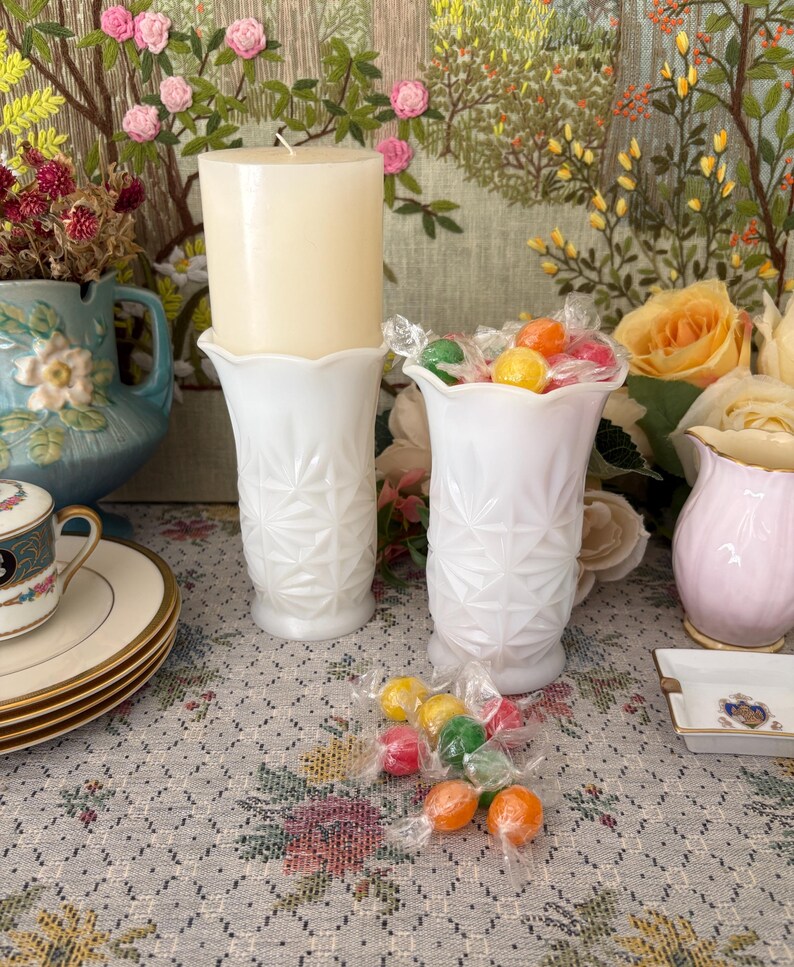 Pu&ograve; includere: Due vasi in vetro opalino bianco con un motivo a stella pressato e bordi smerlati. Un vaso contiene una candela a colonna color crema, mentre l'altro &egrave; riempito con caramelle colorate assortite avvolte in plastica trasparente.