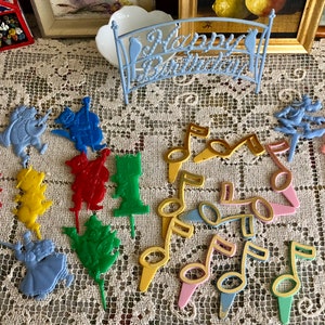 May include: A set of colorful plastic cake toppers featuring musical notes, characters from the Wizard of Oz, and a Mickey Mouse figure. The toppers are perfect for a birthday party or other celebration.