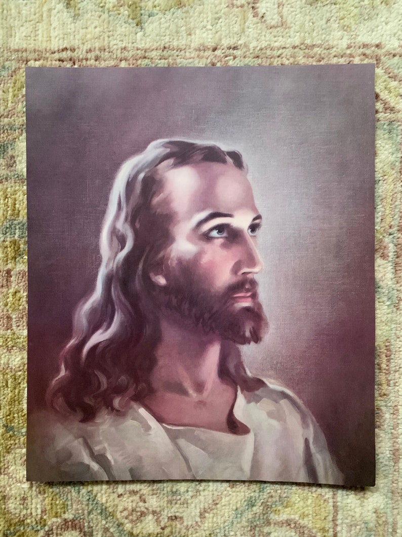 May include: A vintage print of a painting depicting a man with long brown hair and a beard. He is wearing a white robe and looking to the right. The background is a soft purple.