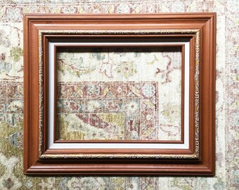May include: A brown wooden picture frame with a gold trim and a white mat. The frame is empty and ready for a photo or artwork.