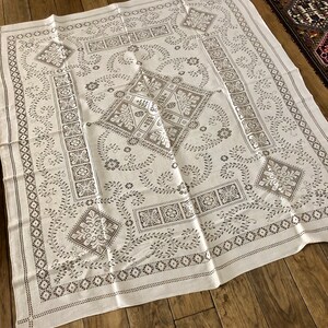 Peut inclure: Nappe blanche avec un d&eacute;licat motif brod&eacute; noir repr&eacute;sentant des motifs floraux et des formes g&eacute;om&eacute;triques complexes.