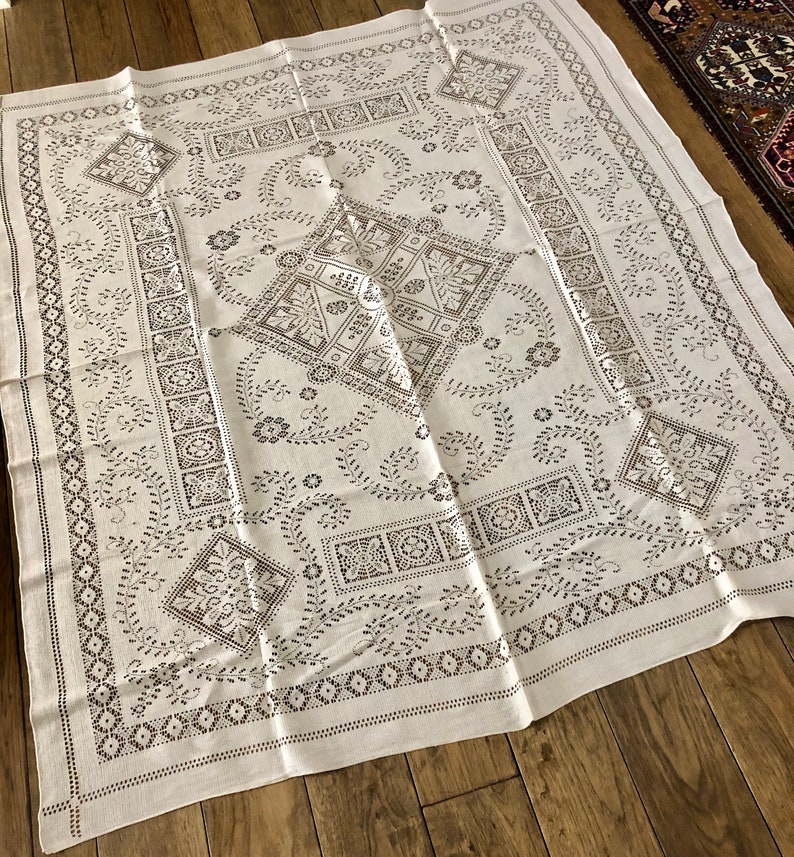 Peut inclure: Nappe blanche avec un d&eacute;licat motif brod&eacute; noir repr&eacute;sentant des motifs floraux et des formes g&eacute;om&eacute;triques complexes.