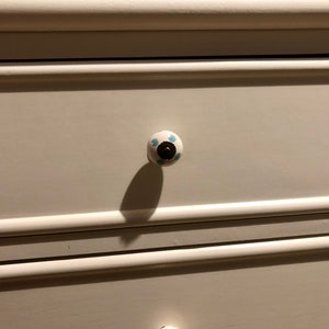 Puede incluir: C&oacute;moda blanca con dos cajones. El caj&oacute;n superior tiene un pomo de cer&aacute;mica blanca con lunares azules.