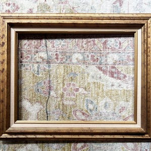May include: A rectangular picture frame featuring a distressed gold finish with a multi-tiered profile. The frame includes an inner border with a light beige fabric-like texture, creating a layered appearance for displaying artwork or photographs.