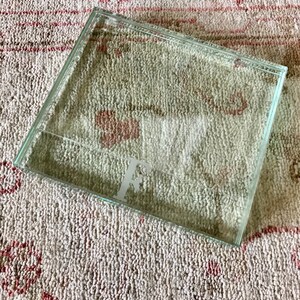 May include: A clear glass tray with a raised edge. The tray has a letter "F" etched into the bottom.
