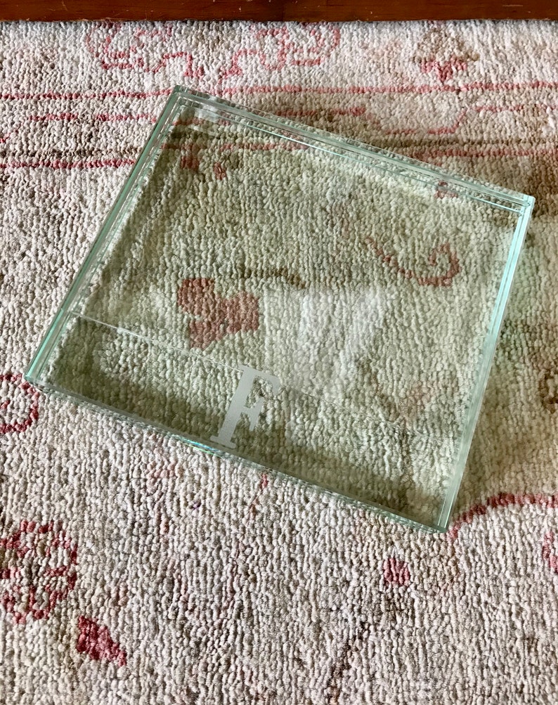 May include: A clear glass tray with a raised edge. The tray has a letter "F" etched into the bottom.