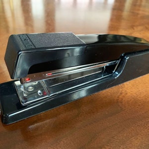 May include: A black stapler with a silver staple mechanism. The stapler has a textured top and a clear plastic window to view the staples.
