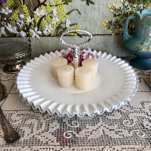 Puede incluir: Bandeja de servir de dos niveles de vidrio de leche blanco con borde plateado y asa plateada. La bandeja est&aacute; decorada con un borde festoneado y tiene cuatro velas votivas en el nivel superior.