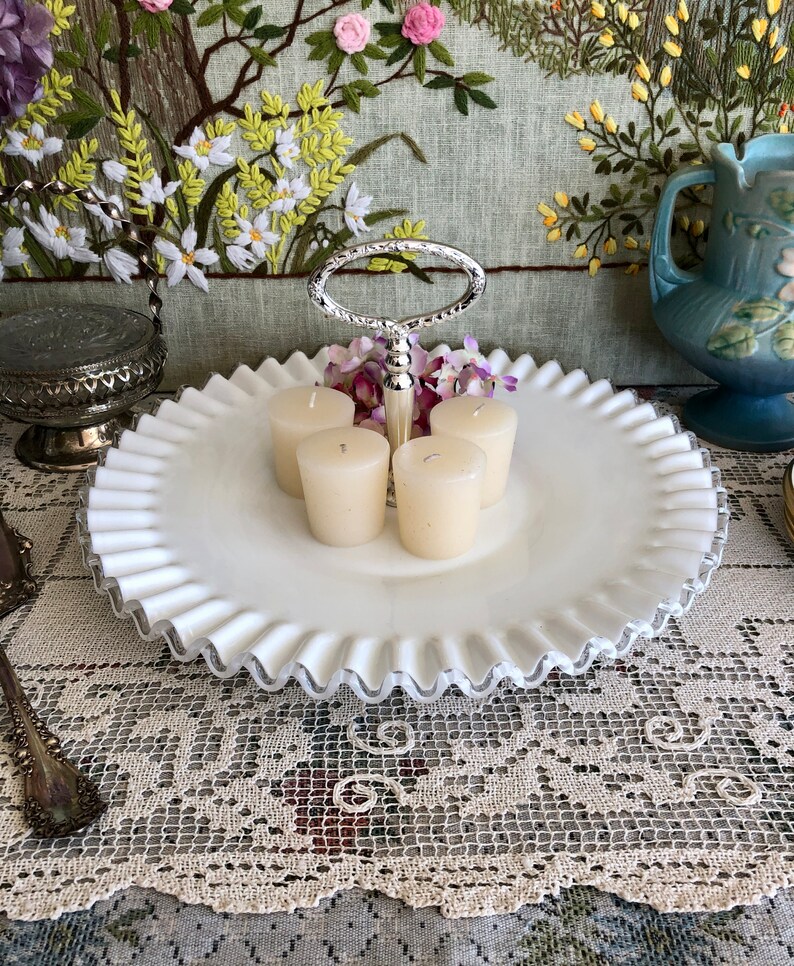 Puede incluir: Bandeja de servir de dos niveles de vidrio de leche blanco con borde plateado y asa plateada. La bandeja est&aacute; decorada con un borde festoneado y tiene cuatro velas votivas en el nivel superior.