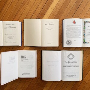 Op de afbeelding: Een bovenaanzicht van zes open boeken op een houten oppervlak. De boeken tonen titels als "Oude Testament", "Essentials of Bible History" en "The New American Bible". De pagina's zijn wit met zwarte tekst.