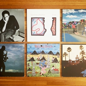 May include: Six vinyl records with different album covers. The covers feature a man in a suit, a colorful abstract design, a swimming pool scene, a man playing a saxophone, a colorful landscape, and a palm tree scene.