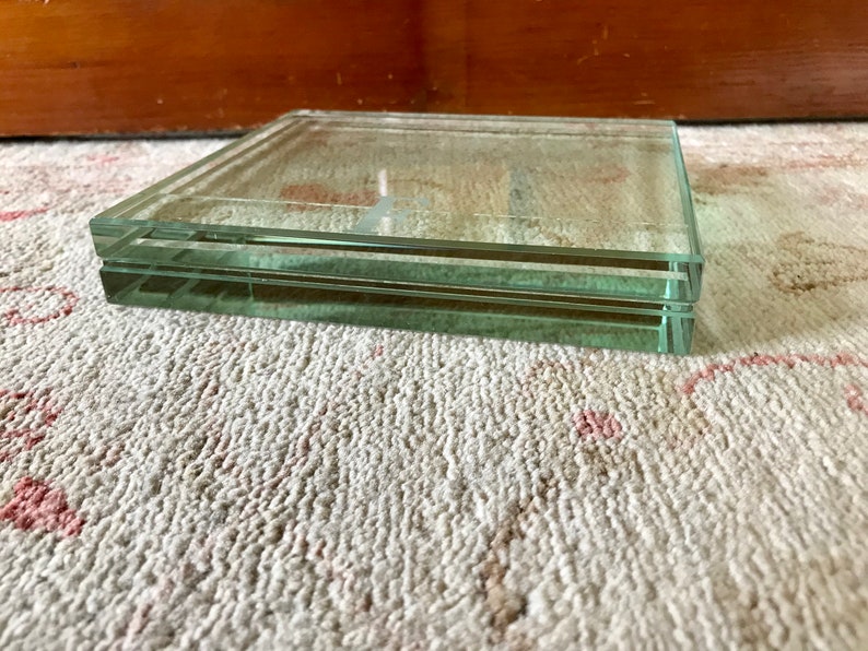 May include: A clear glass square tray with two layers. The tray is sitting on a white carpet with pink accents.