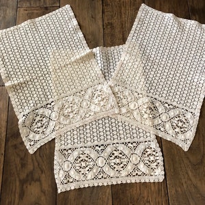 May include: Ivory-colored lace doilies with a floral pattern border. The doilies are arranged on a wooden surface. The lace has a delicate, open weave design, perfect for home decor.