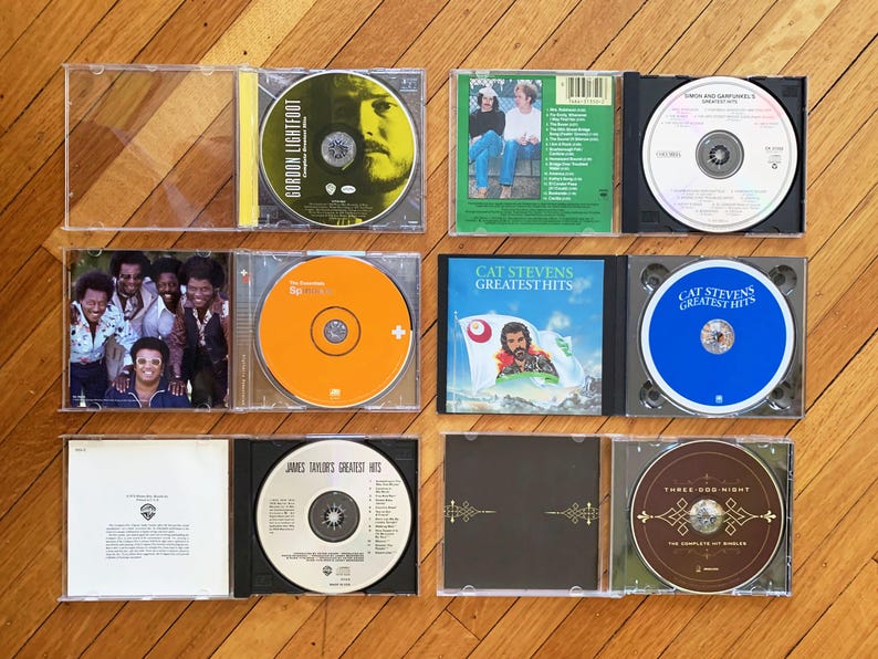 May include: A collection of ten vinyl records in clear plastic cases. The records are arranged in two rows of five. The records are all different colors and have different titles. The titles include "Gordon Lightfoot", "Cat Stevens Greatest Hits", "James Taylor's Greatest Hits", and "Three Dog Night".