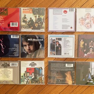 May include: A collection of 10 vintage vinyl records, including albums by The Animals, Bread, Neil Diamond, The Hollies, and The Who. The records are in various colors, including red, blue, green, and yellow. The records are arranged in two rows of five.