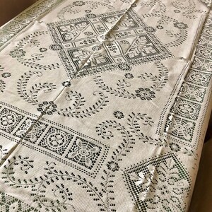 Peut inclure: Une nappe blanche avec un motif de dentelle noire d&eacute;licat. Le motif pr&eacute;sente des motifs floraux complexes et des formes g&eacute;om&eacute;triques.