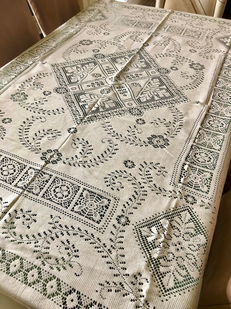 Peut inclure: Une nappe blanche avec un motif de dentelle noire d&eacute;licat. Le motif pr&eacute;sente des motifs floraux complexes et des formes g&eacute;om&eacute;triques.