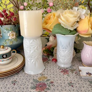 Pu&ograve; includere: Due vasi in vetro opalino bianco con un motivo geometrico a stella. Un vaso contiene una candela cilindrica color crema, mentre l'altro ospita un bouquet di rose artificiali gialle e bianche.