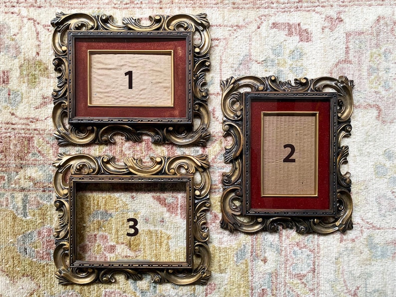 May include: Three ornate gold picture frames with red mats and numbers 1, 2, and 3 in the center of each frame.