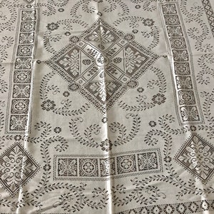 Peut inclure: Nappe blanche avec un motif brod&eacute; noir repr&eacute;sentant des motifs g&eacute;om&eacute;triques et floraux r&eacute;p&eacute;titifs.