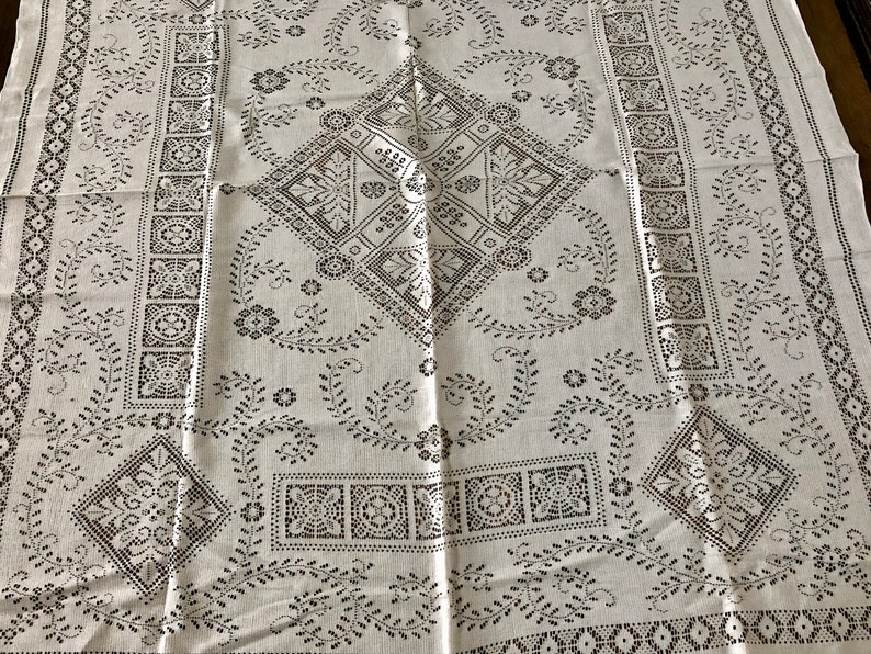 Peut inclure: Nappe blanche avec un motif brod&eacute; noir repr&eacute;sentant des motifs g&eacute;om&eacute;triques et floraux r&eacute;p&eacute;titifs.