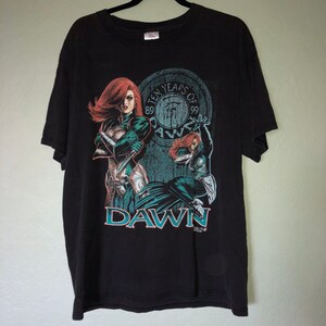 May include: Black t-shirt featuring a comic book graphic of a red-haired woman in a green and silver outfit. The design includes the word "DAWN" and the text "TEN YEARS OF DAWN 89-99".