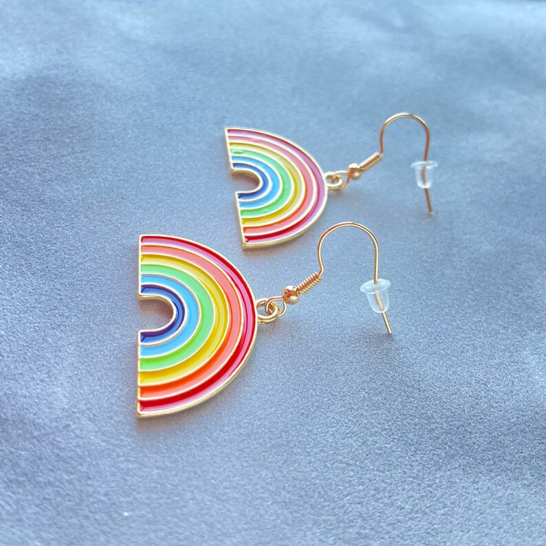 May include: A pair of gold rainbow earrings with a rainbow arch design. The earrings have a hook fastening.