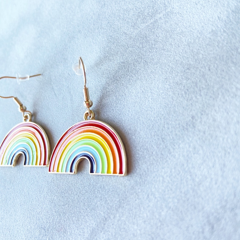 May include: A pair of gold-tone rainbow earrings. The earrings are shaped like rainbows with multiple coloured stripes.