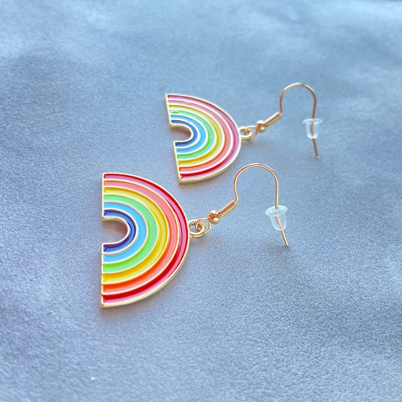 May include: A pair of gold rainbow earrings with a rainbow arch design. The earrings have a hook fastening.