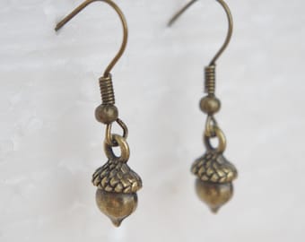 May include: A pair of bronze acorn dangle earrings. The earrings are made of metal and have a simple design.