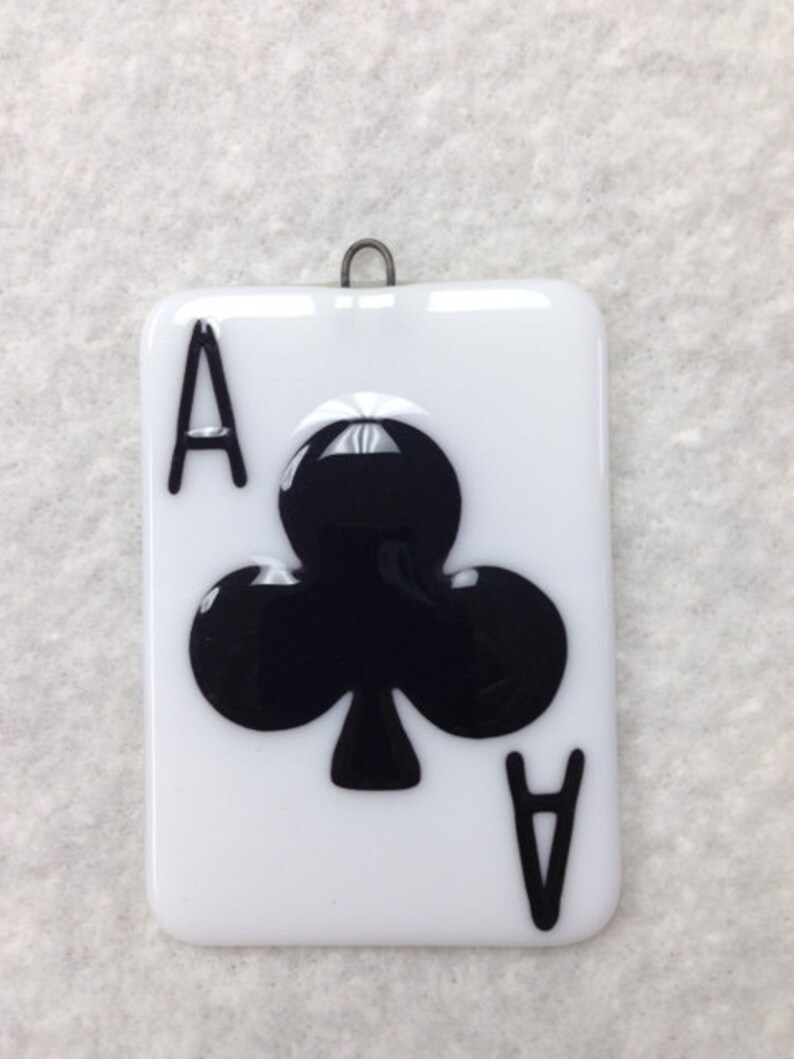 May include: A white glass ornament shaped like a playing card with a black ace of clubs design.