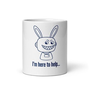 May include: A white ceramic mug featuring a dark blue line art illustration of a robotic rabbit character with large ears and a wide, toothy grin. Below the character, the text "I'm here to help..." is printed in a dark blue sans-serif font.