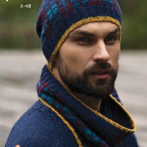Puede incluir: Un conjunto de gorro y braga de cuello de punto azul marino con un estampado de cuadros en color turquesa y burdeos. El gorro y la braga de cuello tienen un ribete amarillo. La palabra "FAROE" está impresa en blanco en la parte superior de la imagen, y las palabras "JODY LONG ALBA COLLECTION" están impresas en la parte inferior.