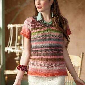 Puede incluir: Un top de punto de manga corta con cuello en V, con rayas horizontales en tonos rosa, naranja, verde y gris. El patrón de punto presenta una textura. Se lleva una camisa verde claro debajo.