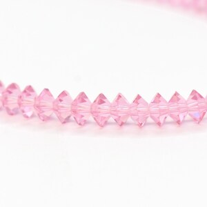 Puede incluir: Una hebra de cuentas de cristal rosa, cada cuenta es facetada y tiene una forma puntiaguda.