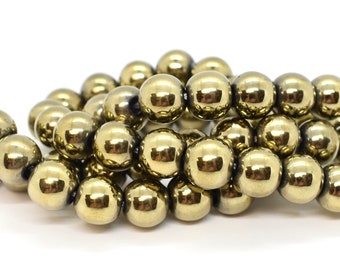 May include: A strand of gold-toned round beads. The beads are smooth and shiny, and they are strung together on a clear thread.