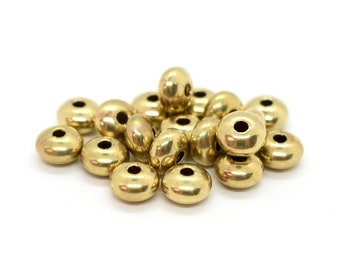 May include: A pile of gold-colored metal beads, each with a round shape and a hole in the center.