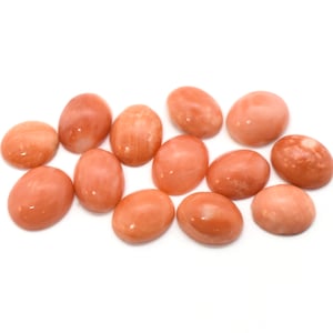 May include: A collection of 12 oval-shaped, smooth, polished, light pink and orange gemstones. The stones have a natural, marbled appearance.