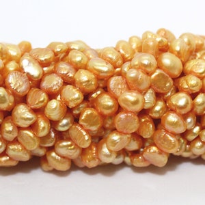 以下が含まれることがあります： 金色で虹色の淡水真珠の糸。真珠は不規則な形をしていて、滑らかで光沢のある仕上がりです。