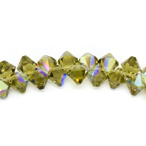 May include: A strand of faceted, olive green crystal beads with an iridescent finish. The beads are strung on a clear thread and are approximately 6mm in diameter.