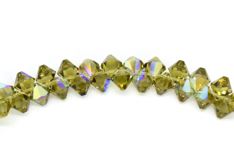 May include: A strand of faceted, olive green crystal beads with an iridescent finish. The beads are strung on a clear thread and are approximately 6mm in diameter.