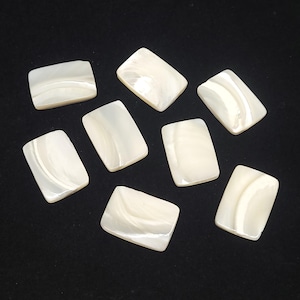 May include: Eight white rectangular mother of pearl shell tiles with a pearlescent sheen.