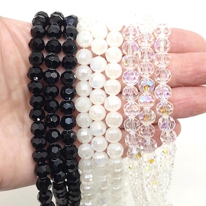 May include: Three strands of faceted glass beads. One strand is black, one is white, and one is clear with an iridescent finish.