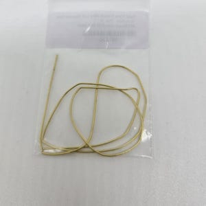 May include: A clear plastic bag containing several gold-colored wire shapes. The wires are bent into geometric forms, with a straight piece extending from the bundle. The bag has a white label with text.
