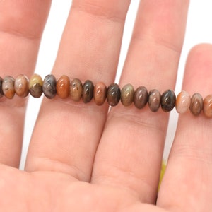May include: A strand of brown, beige, and gray gemstone beads. The beads are round and have a smooth, polished finish.