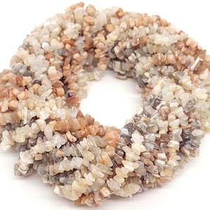 May include: A strand of sunstone chip beads in shades of white, brown, and beige. The beads are irregularly shaped and have a natural, rough texture.