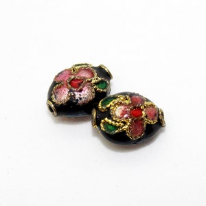 May include: Two black oval beads with gold trim and floral designs in pink, red, and green.